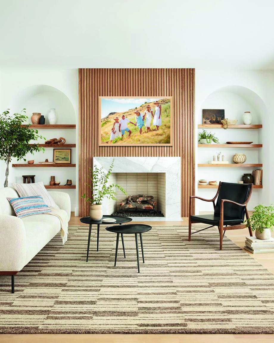 A framed family portrait above a fireplace in a light, modern living room